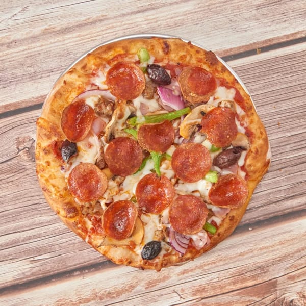 A whole pepperoni pizza with various toppings sits on a rustic wooden table.