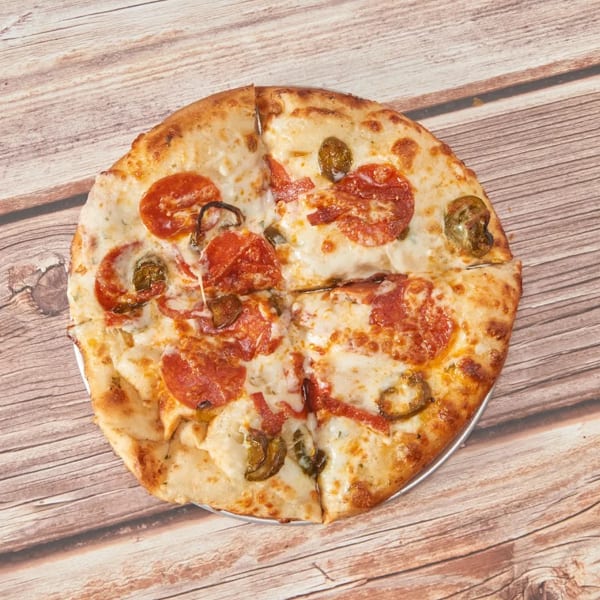 A whole pepperoni and jalapeño pizza, cut into four slices, on a wooden table.